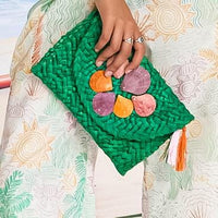 Green straw clutch adorned with pink and purple shells